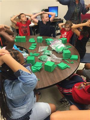 Kids at table with green construction paper 