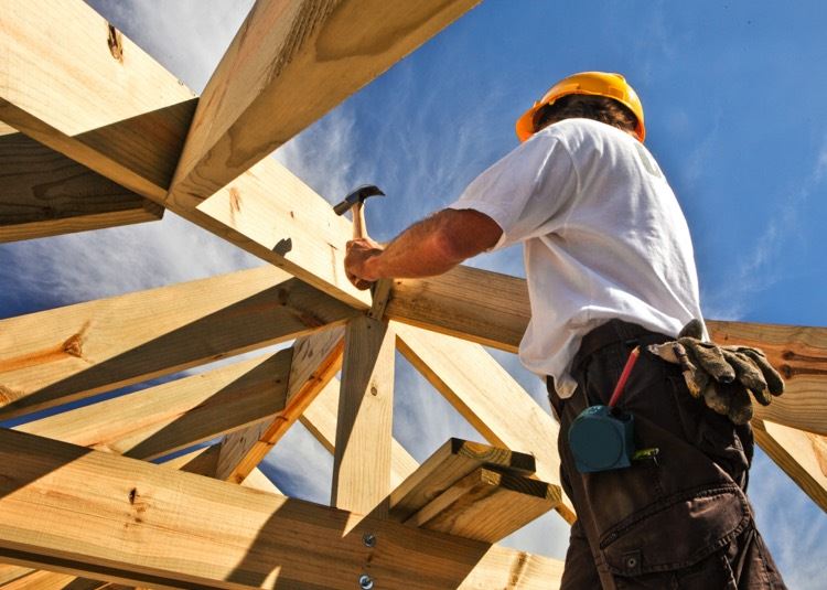 Cnstruction worker fixes the wooden frame of a house