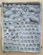 Grey mixed media relief sculpture of a bee hive