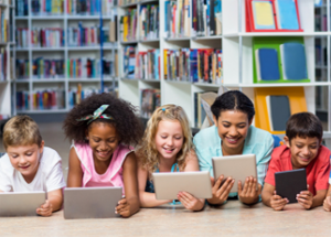 Students next to each other in a library reading digital content off of tablets 