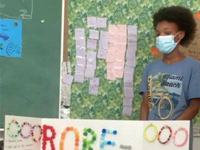 student showing bracelets she made  